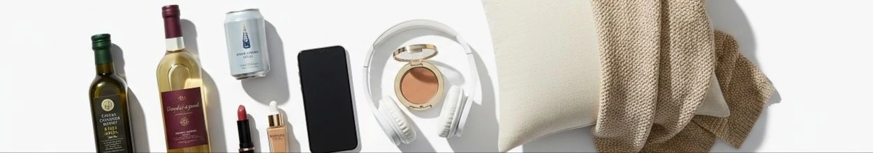 Un assortimento di prodotti di varie categorie: una bottiglia d'olio d'oliva, vino bianco, una lattina di birra, cosmetici, uno smartphone, cuffie bluetooth, un cuscino e una coperta calda.