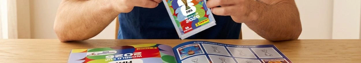 Primo piano di una persona seduta a un tavolo di legno mentre apre una bustina di figurine Panini della FIFA World Cup 2026. Davanti a sé ha l'album ufficiale aperto, pronto per essere completato con le figurine dei calciatori.