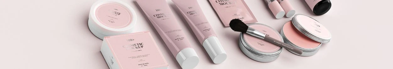 Packaging beauty rosa disposti ordinatamente su un piano, comprendenti creme di varie dimensioni, un pennello per trucco, ciprie, fondotinta e stick per labbra.