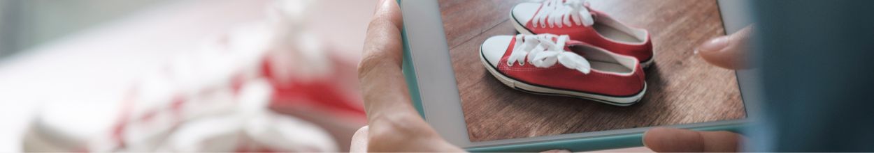 Persona che inquadra un paio di scarpe rosse con lo smartphone usando la fotocamera.