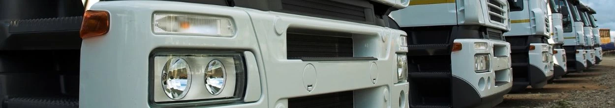 Primo piano della parte anteriore di una serie di camion bianchi allineati all'aperto.